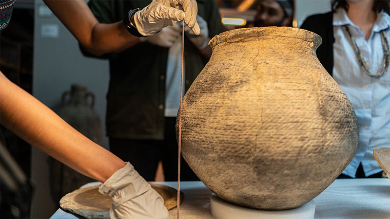 Photo of a person measuring a pottery artifact